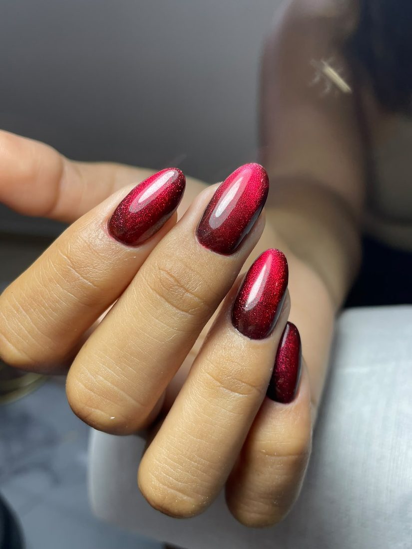 Uñas almendradas en rojo oscuro con efecto ojo de gato