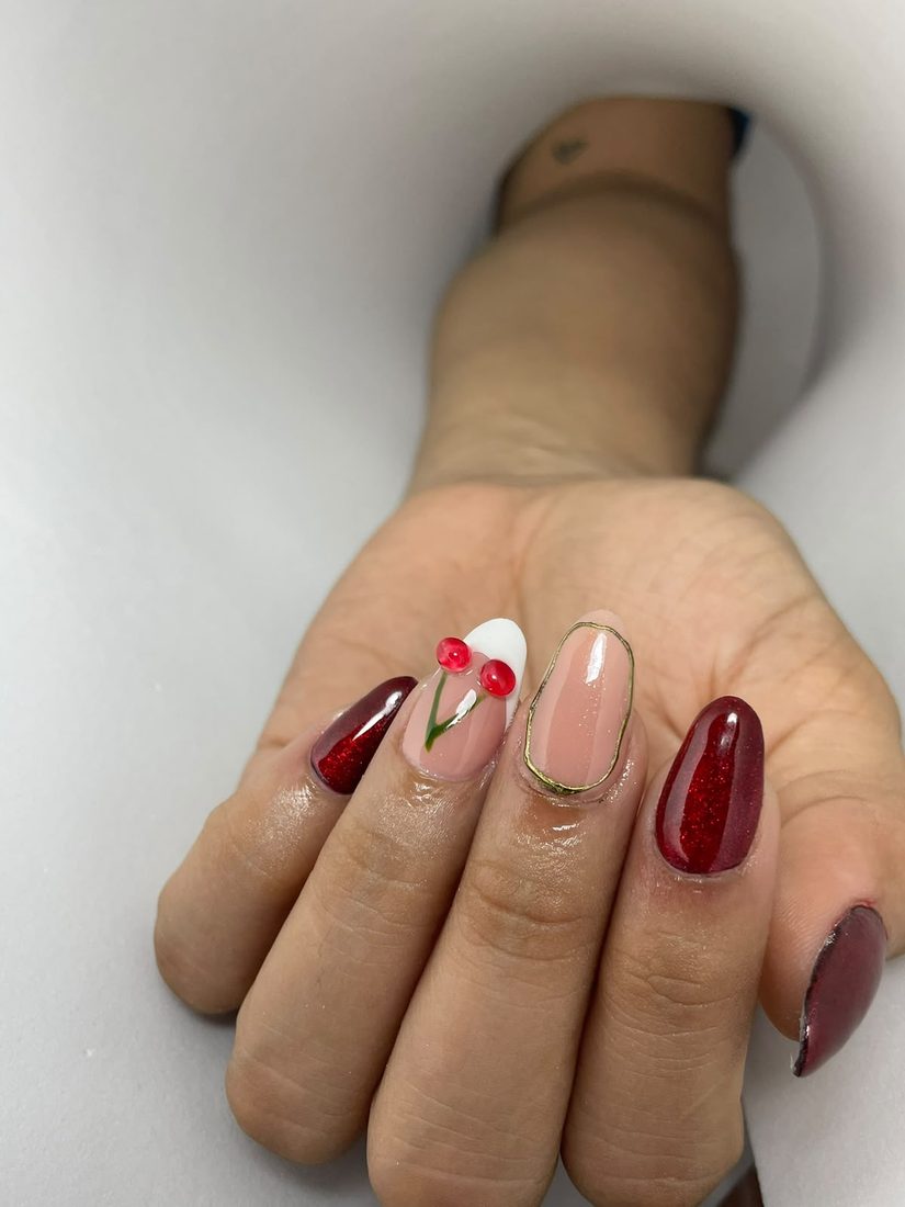 Uñas en vinotinto brillante con una uña decorada con cerezas en relieve